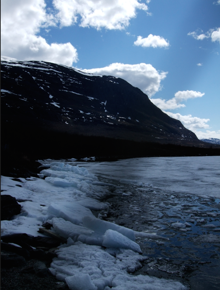 scene of snow beside open water in mountains